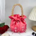 Sac seau en satin rose avec poignée en perles colorées et pendentifs pour soirées élégantes. - Rose rouge