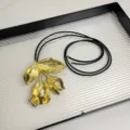 Exquisites Detail einer goldenen Metallblumen-Halskette mit einer schicken schwarzen Lederkordel. - Blumenstil (Z-2887) / Gold