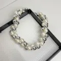 Nahaufnahme einer Statement-Kette mit abwechselnden Perlen und glänzenden Metallkugeln. - Silber Weiß Perlenstil (Z-2060) / Silber und Weiß