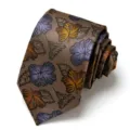 Close-up detail of brown men's jacquard tie featuring elegant blue and yellow floral pattern. - Brown