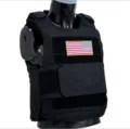 Black tactical vest detail featuring durable fabric, MOLLE webbing, and patch for training. - One Size / Black