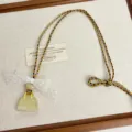 Detail shot of the charming mini handbag pendant necklace featuring a delicate lace bow and colorful cord. - Yellow