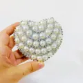 Close-up detail of a sparkling heart-shaped evening clutch with pearls and rhinestones. - Arc Shape Style / Silver