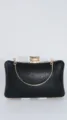 Black evening clutch bag detail shot showing gold metal chain handle and sparkly fabric. - Black
