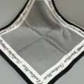Detailed shot of black and white houndstooth silk square scarf with classic border text. - SJ1102-JKF