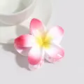 Detail view of a cute jelly pink plumeria flower hair claw clip for summer style. - Rose Red with Yellow Stamen