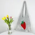 Detailansicht der grauen Strick-Netztasche mit rotem Erdbeermuster und langen Schulterriemen. - Silber