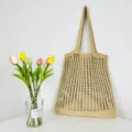 Detailansicht einer lässigen beige Strick-Tragetasche mit Blumen-Dekor auf Tisch. - Khaki