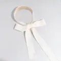 Primer plano de una diadema de cinta de encaje estilo coreano con un diseño de lazo delicado. - Beige