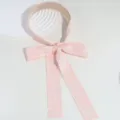 Gros plan détaillé du serre-tête en dentelle rose avec un joli nœud et de longs rubans. - Rose