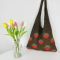 Bruine gebreide aardbei tote tas detail met schattig patroon en zachte stof textuur. - koffiekleur