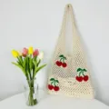 Vista dettagliata della borsa tote in maglia beige con grazioso motivo a ciliegia e spallaccio. - Beige
