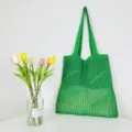 Detail of vibrant green knitted crochet tote bag showing open mesh texture and spacious capacity. - Green