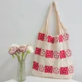 Knitted floral tote bag detail showing the red and white woven square pattern and texture. - Apricot and Red