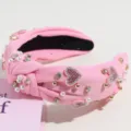Detailed view of pink knotted headband decorated with sparkly rhinestones and faux pearls. - Pink Pearl Rhinestone Heart