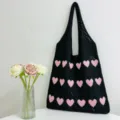 Nahaufnahme der schwarzen Stricktasche mit rosafarbenem Herzmuster und feiner Textur. - Schwarz & Rosa