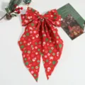 Detalle de pinza de pelo con lazo rojo navideño, accesorio festivo con estampado. - Rojo