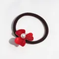 Detailed shot of the red acetate flower hair tie with a faux pearl center, ponytail holder. - Red