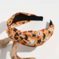 Halloween headband detail view featuring cute ghost pumpkin cat pattern on wide fabric knot design. - Orange