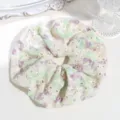 Close-up detail of a sweet floral embroidered hair scrunchie with delicate eyelet lace design. - Purple Embroidered Hollow