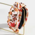 Close-up view of autumn maple leaf print knotted headband with rhinestones and pearls. - Rhinestone Maple Leaf