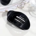 Detailaufnahme einer eleganten schwarzen ovalen Haarklammer, minimalistisches Haaraccessoire. - Glänzendes Schwarz