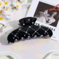 Close-up detail of black rhinestone hair claw clip with white lattice pattern, stylish hair accessory. - Black Lattice