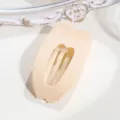 Dettaglio ravvicinato di una pinza per capelli ovale a cuore, ideale per chignon eleganti. - Beige