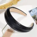 Primer plano detallado de una elegante diadema ancha de piel de serpiente negra. - Negro
