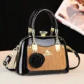 Primo piano dettagliato della borsa in pelle verniciata nera monogrammata con elegante ciondolo floreale. - Marrone