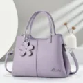 Borsa in pelle viola con motivo litchi e ciondolo a fiore, elegante vista di dettaglio dei metalli. - Viola