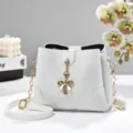 Elegante borsa a secchiello bianca con catena dorata e ciondolo a fiocco da donna. - Bianco