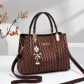 Retro brown textured handbag with top handles, crossbody strap, and elegant clover charm. - Coffee