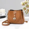 Borsa secchiello in pelle PU marrone con tracolla a catena e ciondolo a fiocco, elegante. - Marrone