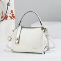 White mini top handle crossbody bag with floral embossed pattern and elegant gold lock hardware. - White