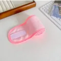 Detalle de diadema de spa de felpa rosa que muestra tela de toalla y cierre de velcro. - Rosa oscuro