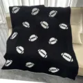 Dettaglio in primo piano della coperta soffice nera con motivi da football su un comodo divano. - Palla da rugby / Nero