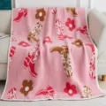 Pink knit blanket featuring stylish cowboy boots and cute floral patterns, detail shot. - Red and Brown Boots