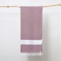 Detailed shot of a woven jacquard Turkish towel featuring a stylish diamond pattern and fringe. - Burgundy