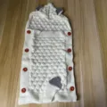 Knitted baby sleeping bag with cute animal ears and red buttons detail close-up. - Milk White