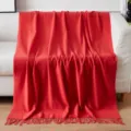 Detail shot of a soft red throw blanket with fringe, cozy home decor for living room sofa. - Solid Color Throw Blanket - Bright Red