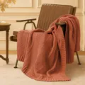 Detailed view of the cozy knitted blanket draped over a chair, perfect for sofa and office. - Coffee