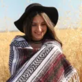 Detail shot of the woven mexican blanket showcasing its unique texture, fringe and rustic setting. - 150x200cm (1.2kg) / Wine Red & Grey