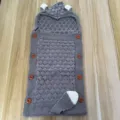 Detailed view of the gray knitted baby sleeping bag with cute animal ears and wooden buttons. - Dark Gray