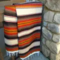 Detailed close-up of a vibrant woven Mexican blanket featuring colorful stripes and fringe. - 35*210 200g / Beige
