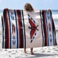 Woven beach blanket detail showcasing traditional thunderbird pattern and aztec geometric stripes. - Beige
