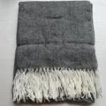 Close-up view of stylish black and white herringbone throw blanket with elegant fringe. - Black