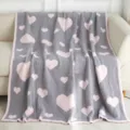 Cozy grey plush knit blanket with pink heart pattern draped softly over a modern sofa. - Grey & Pink Hearts
