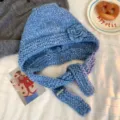 Nahaufnahme einer blauen handgemachten groben Strickmütze mit zarter dreidimensionaler Blume. - Blau