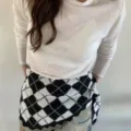 Detail shot of a vintage black and white argyle knit triangular scarf styled at the waist. - Black